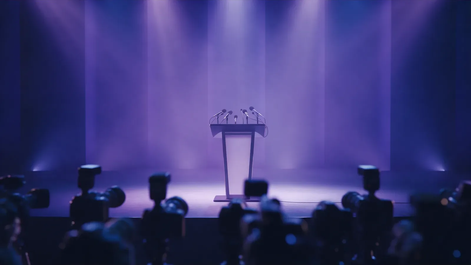 A press stage with a podium and cameras